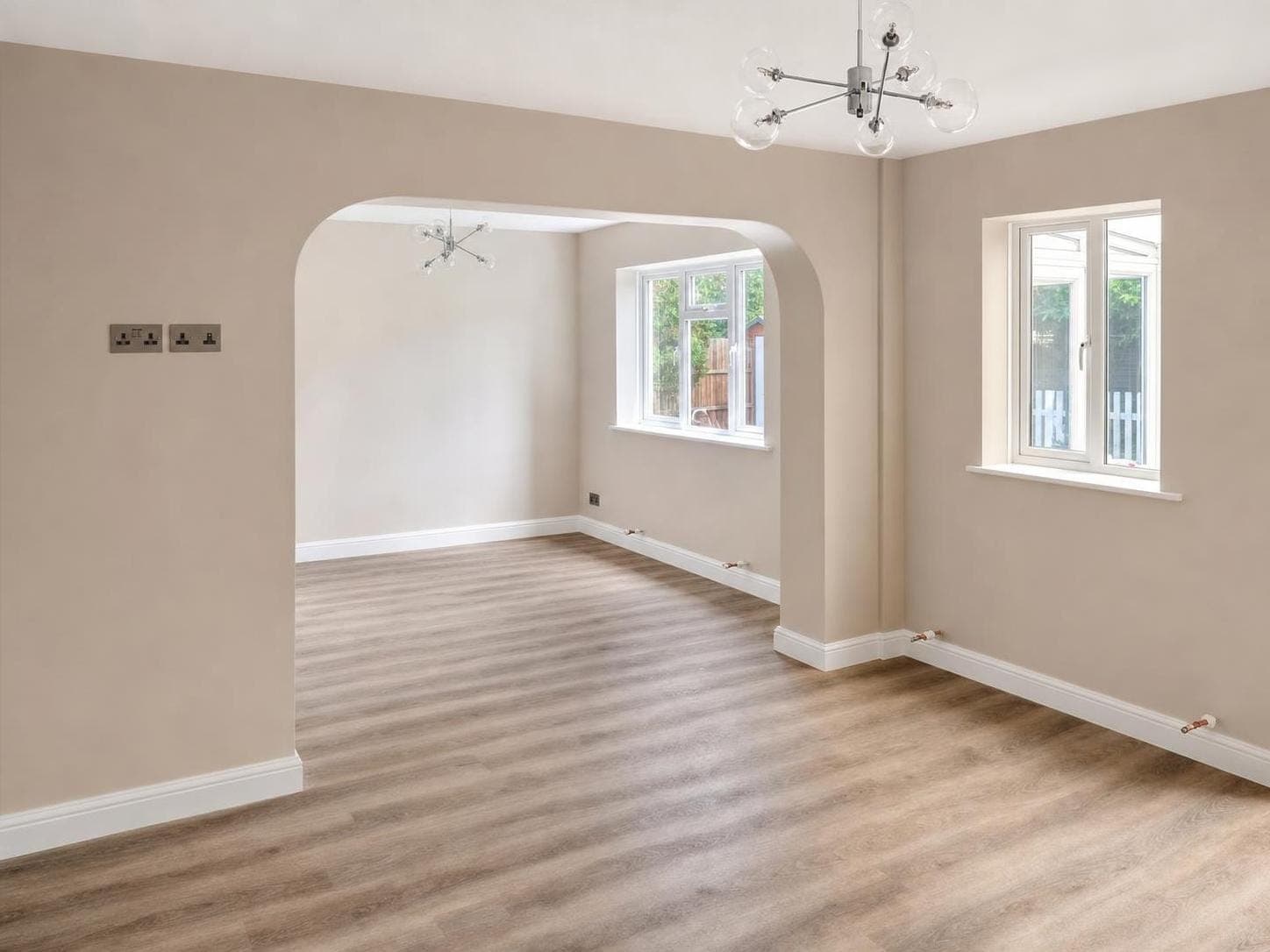 Open-plan living room with warm beige walls, white ceiling, white skirting boards and architrave around openings.