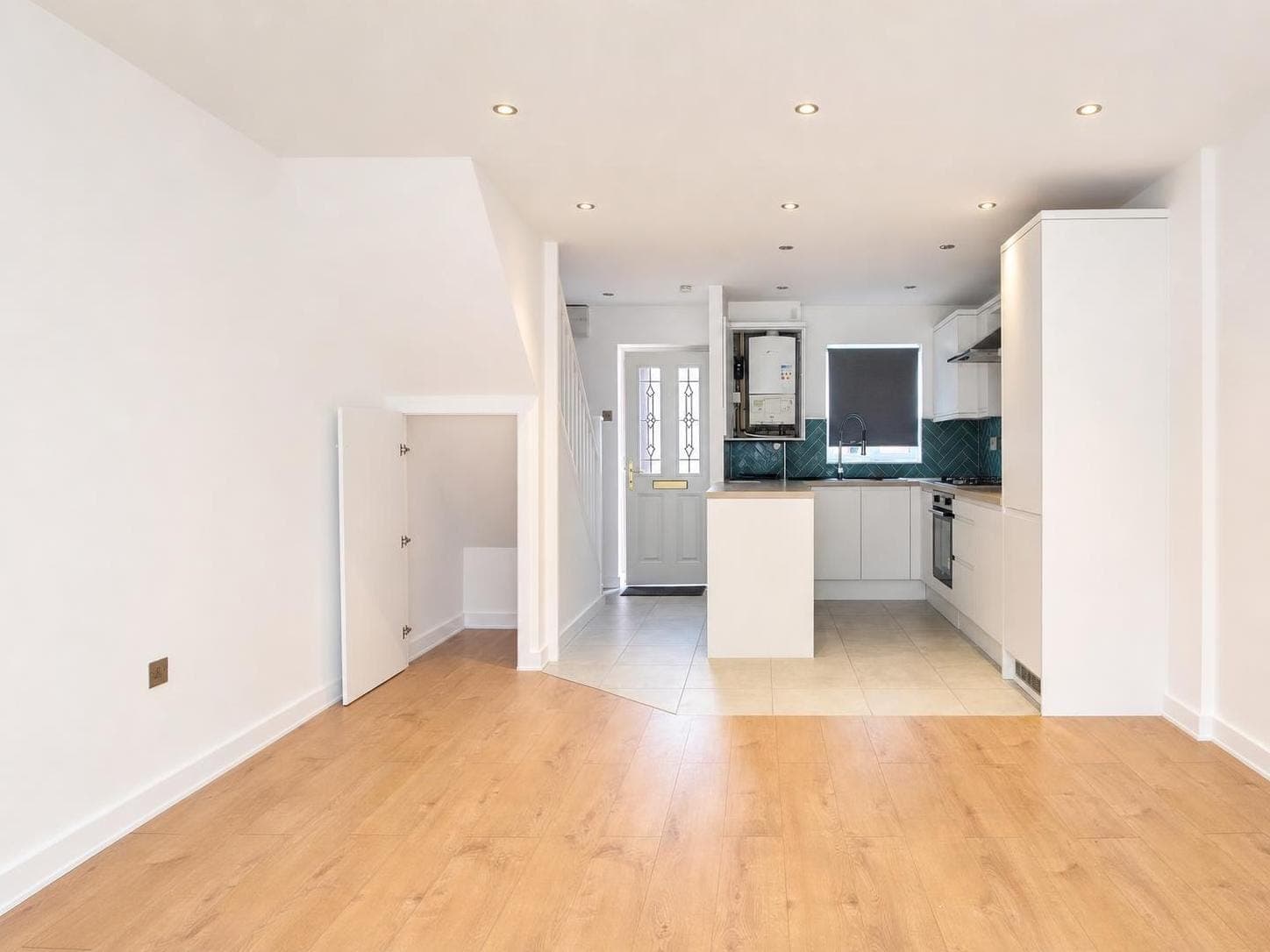Open-plan living and kitchen area with cream walls, white painted doors, door frames and skirting boards, and a white island unit