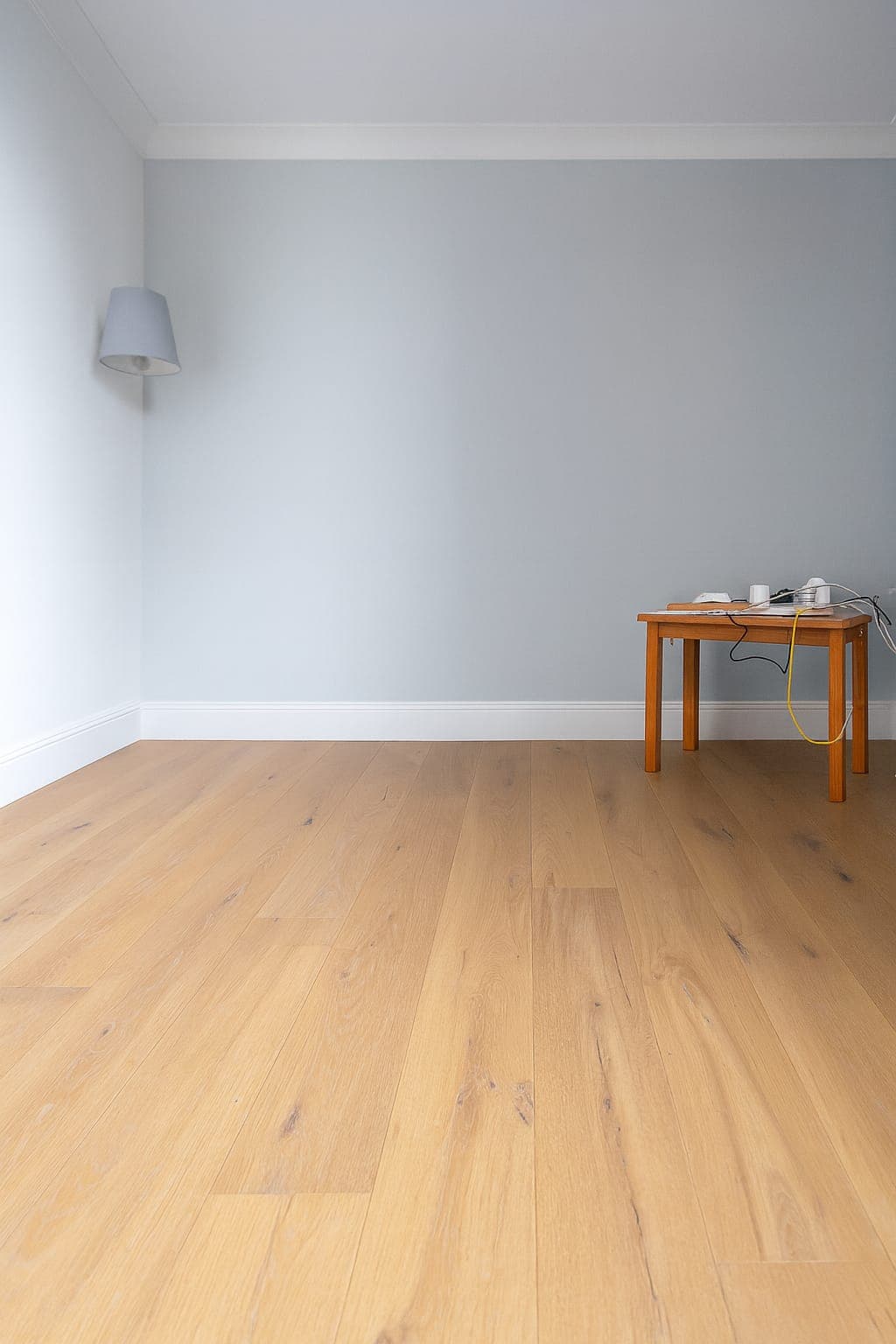 Empty bedroom with pale painted walls, white skirting boards, wooden floor and ceiling cornice